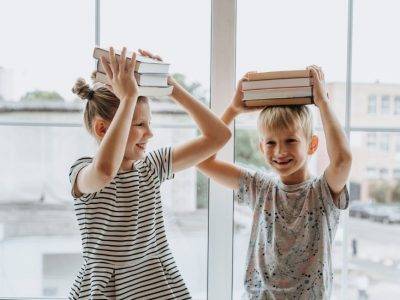 deux enfants tenant des livres jeunesse au-dessus de leur tête