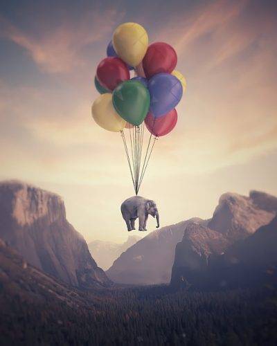 éléphant transporté par des ballons entre des montagnes